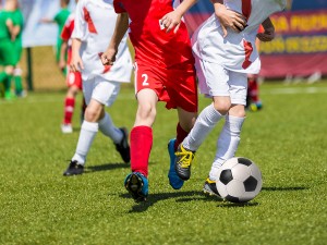 Young boys playing football soccer game. Running players in red and white uniforms